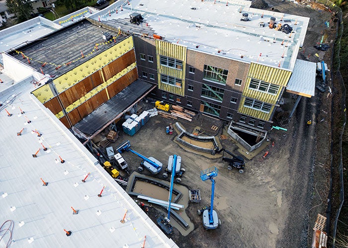 looking down between two wings of an unfinished building to where some planters are installed