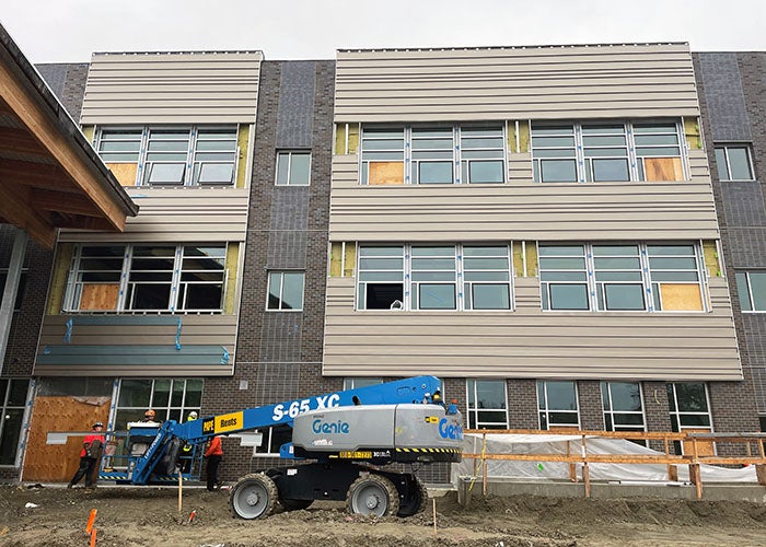 a part of a 3-story building with brown siding and windows