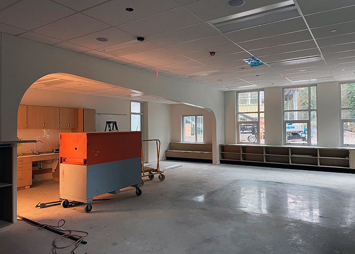 a large room with an arch divider, windows, and cabinetry