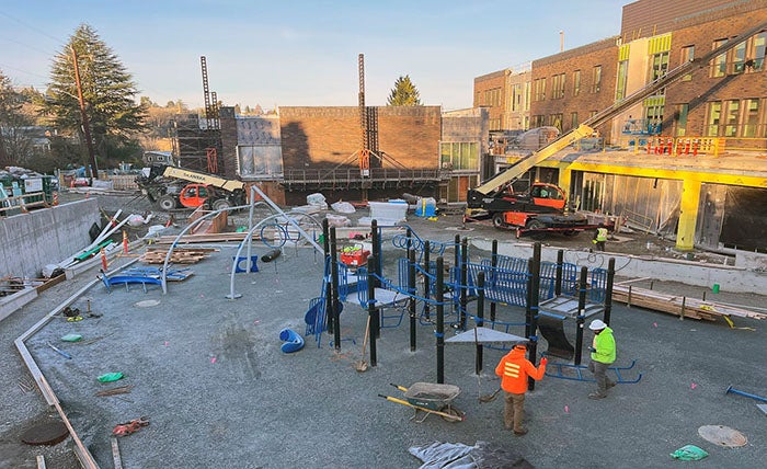 people are installing a play structure outside of a building under construction