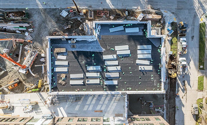 looking down onto a roof with some materials stacked on it with construction work on the ground