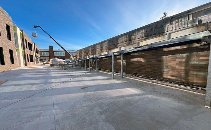 a concrete terrace outside a brick building with no windows has the structure for a ramp up one side