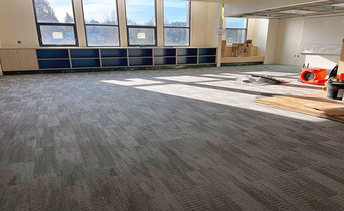 a large room with shelves under the windows has carpet being installed