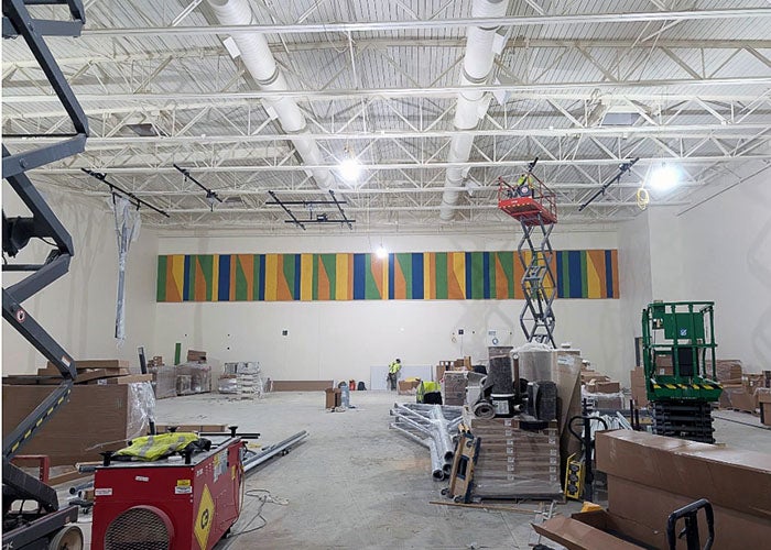 a gymnasium under construction wth a scissor lift and a colorful wall panel