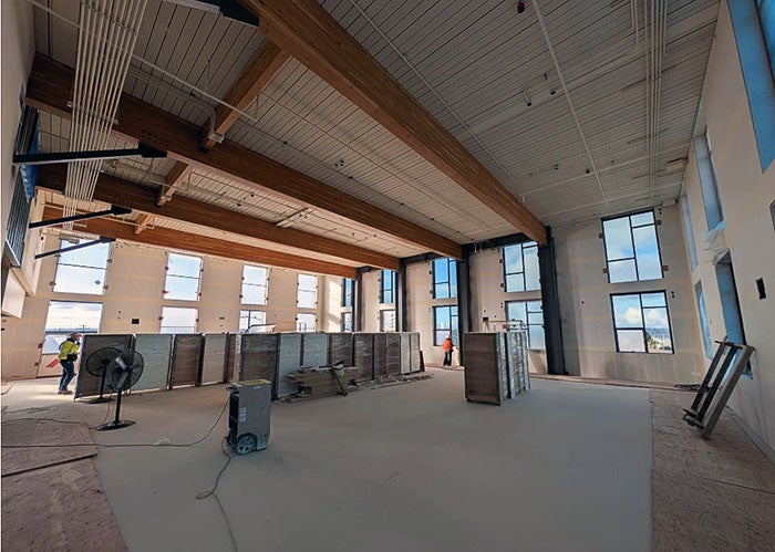 larger room partially completed with wood ceiling, large beams, and windows