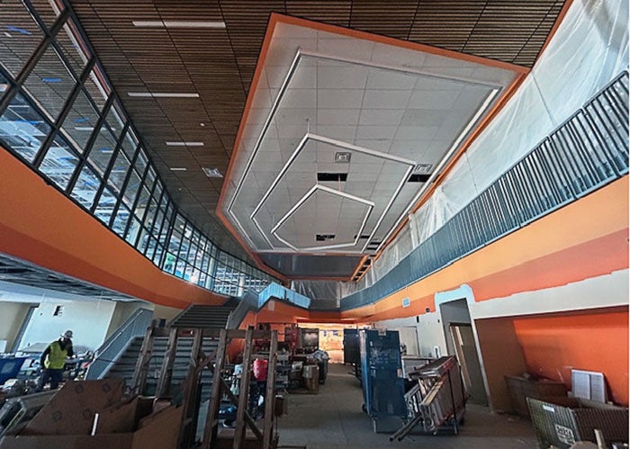 cafeteria under construction with orange stripes on walls and an atrium ceiling