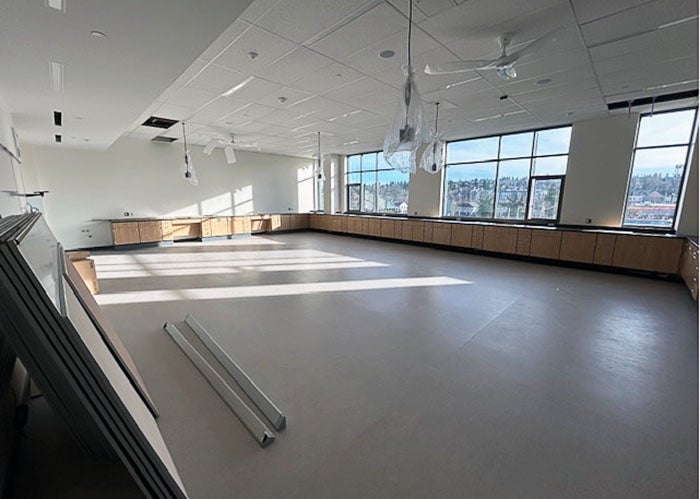 a large open room with cabinets around the edges and power strips hanging from the ceiling