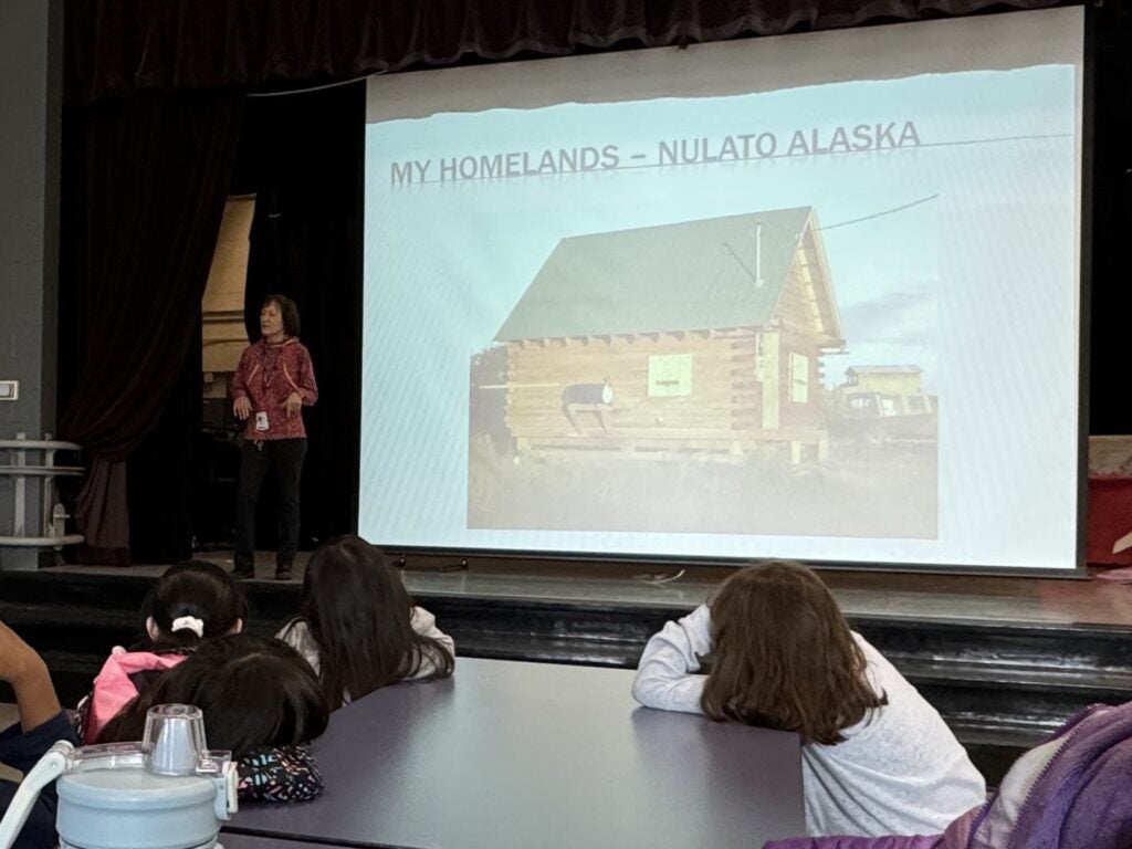 Photo of slideshow and presenter. Title slide reads: My Alaskan Summer