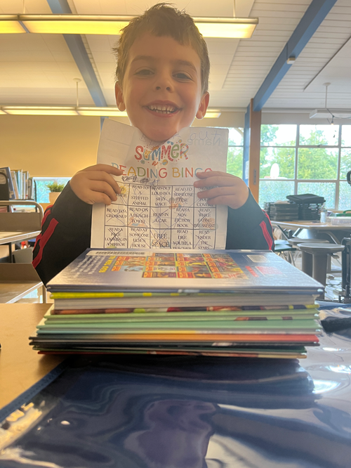 Alki student holding their summer reading bingo card