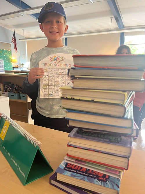 Alki student holding their summer reading bingo card