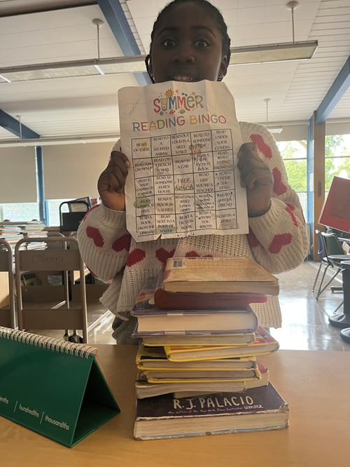 Alki student holding their summer reading bingo card