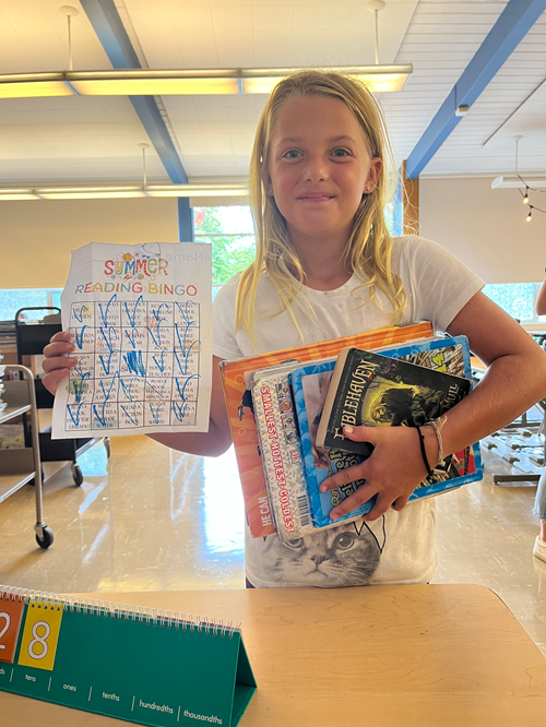 Alki student holding their summer reading bingo card