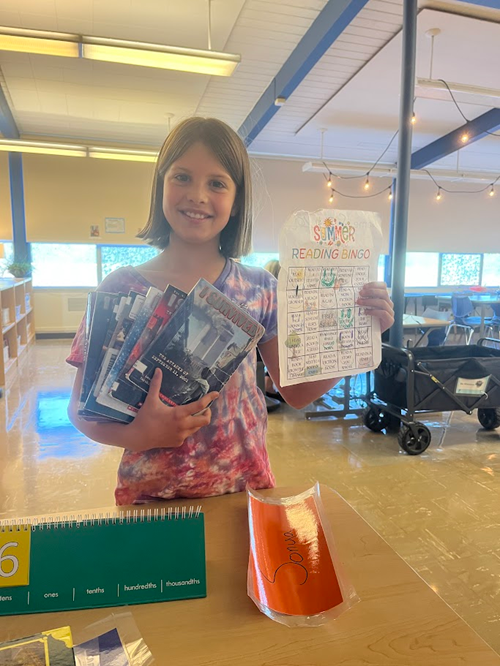 Alki student holding their summer reading bingo card