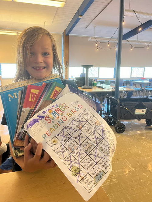 Alki student holding their summer reading bingo card