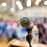 Microphone on podium with audience behind them.