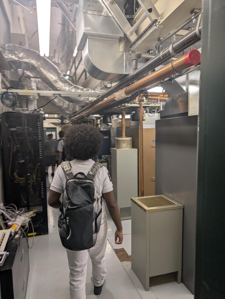 student on field trip underneath pipes in building