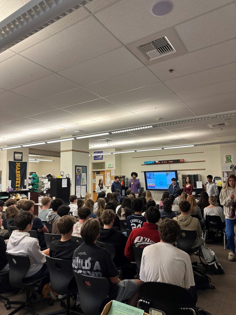 Alumni addresses packed room of DECA students 