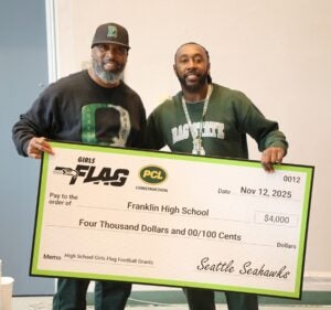 Franklin girls flag football coach holding a check for $4,000