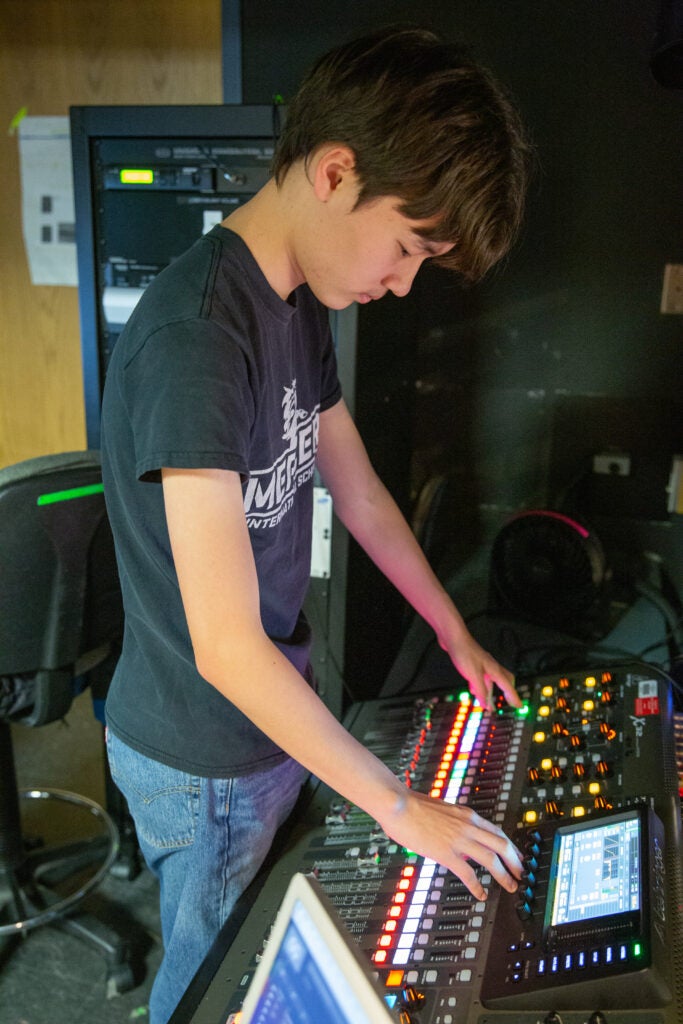 technical theater sound mixing student at a mix board