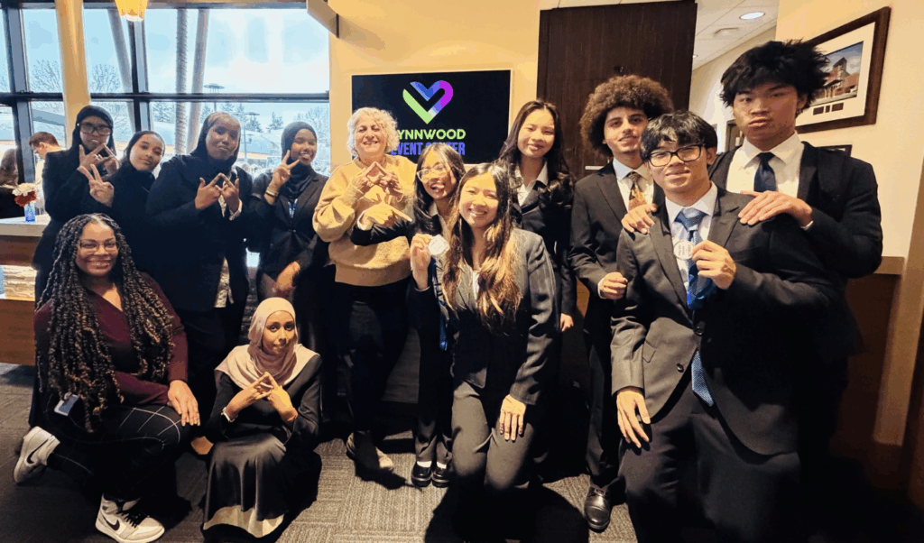 Group of studetns posing in front of heart logo at DECA competition