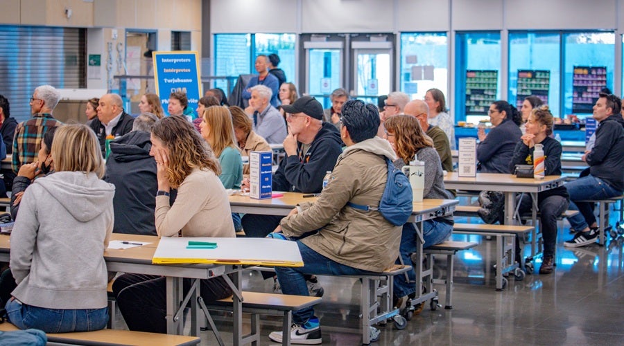 Community members sitting at tables at James Baldwin Elementary School March 26, 2026 community meeting.