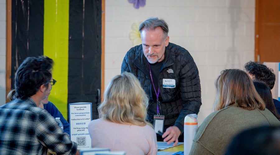 SPS staff member, Mike Starosky, speaking to community members and writing down key points on a poster board at McClure Middle School March 24, 2026 community meeting.