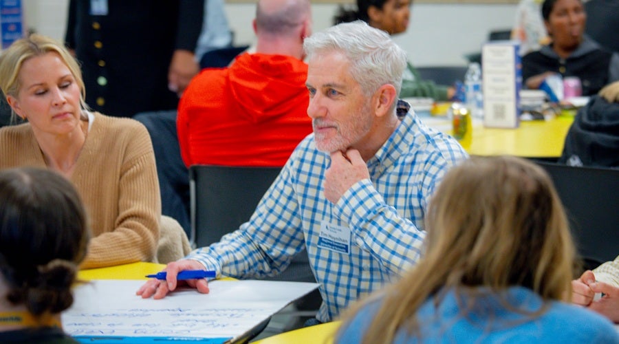SPS staff member, Tim Moynihan, speaking to community members and writing down key points on a poster board at McClure Middle School March 24, 2026 community meeting.