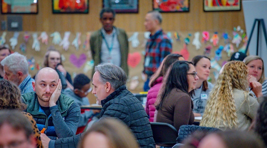 Community members sitting at tables in Salmon Bay K-8 school March 10, 2026 community meeting.