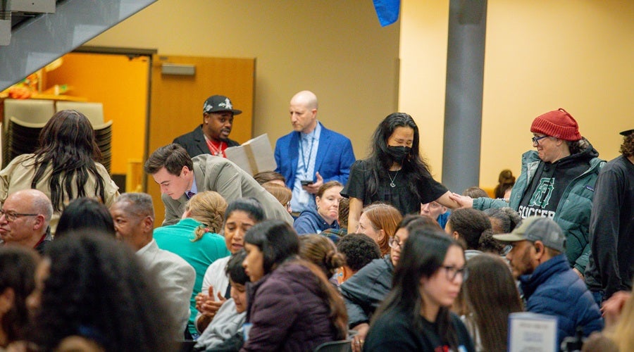 Community members sitting at tables in South Shore Prek-8 School March 3, 2026 community meeting. Superintendent Shuldiner talking to a community member in the background.