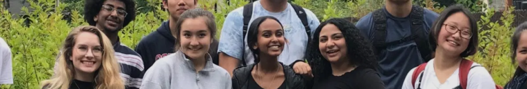 interns lined up and smiling in front of vegetation