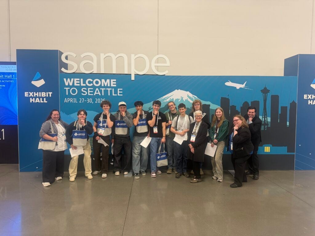 group of students posing in front of sign reading "welcome to seattle sampe"