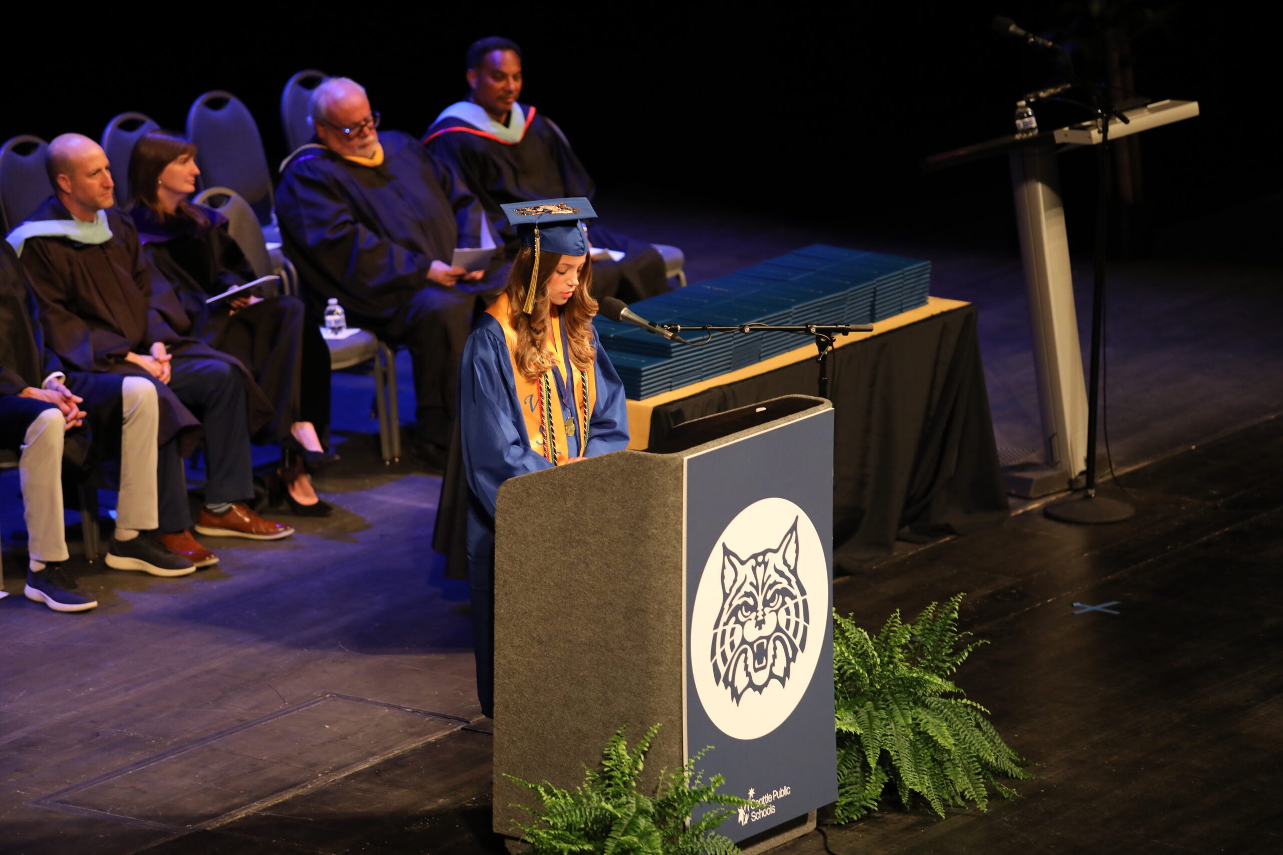 West Seattle Graduation speaker at podium while district leadership looks on