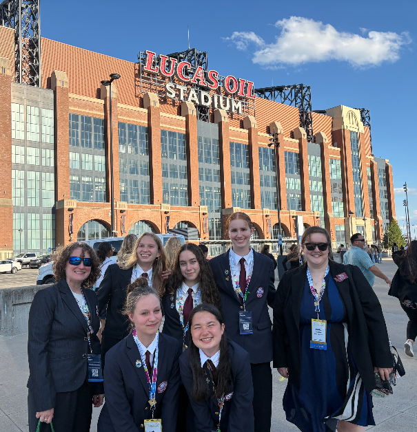 students wearing suits and posing in front of lucas oil stadium