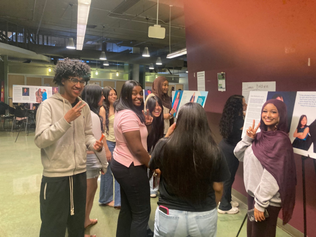 students smiling and posing in front of posters at John Stanford Center