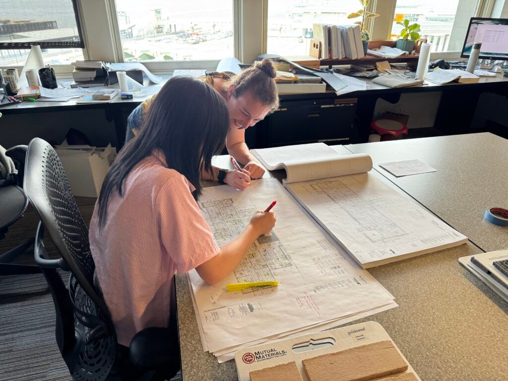 Student reads blueprint with mentor