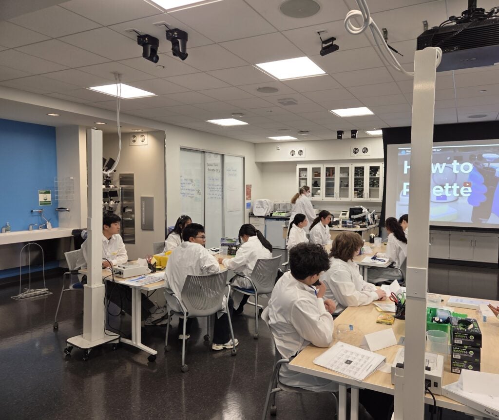 students in labcoats completing pipetting exercise