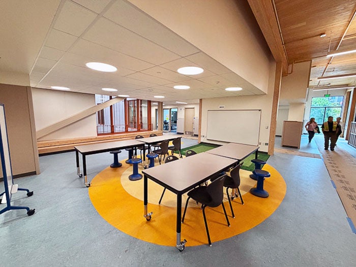 a large open space with a yellow circle in the floor and tables with chairs