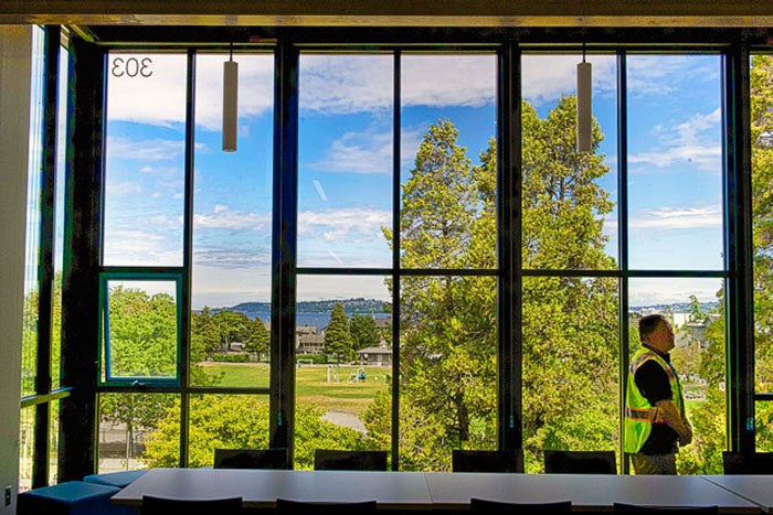 a large window that looks out to trees, sky and water in distance