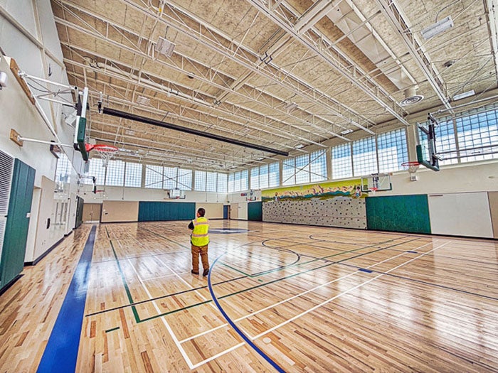 a gymnasium with windows around the top edge and a person in a construction vest in center