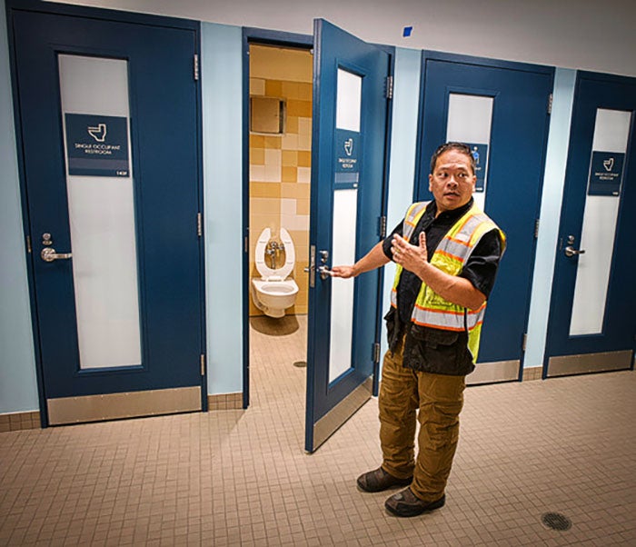 a person in a construction vest opens a door to a toilet room