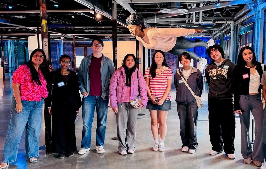 group of students standing in front of sculpture in warehouse setting