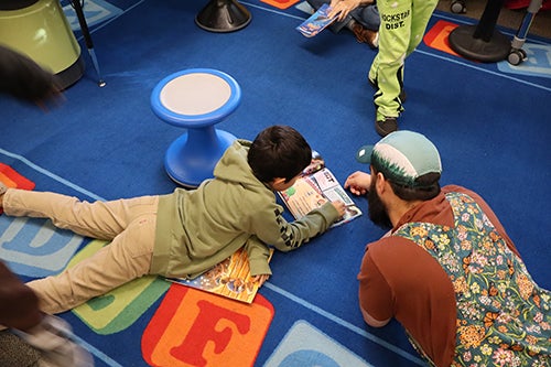 Lowell student and adult reading on the floor
