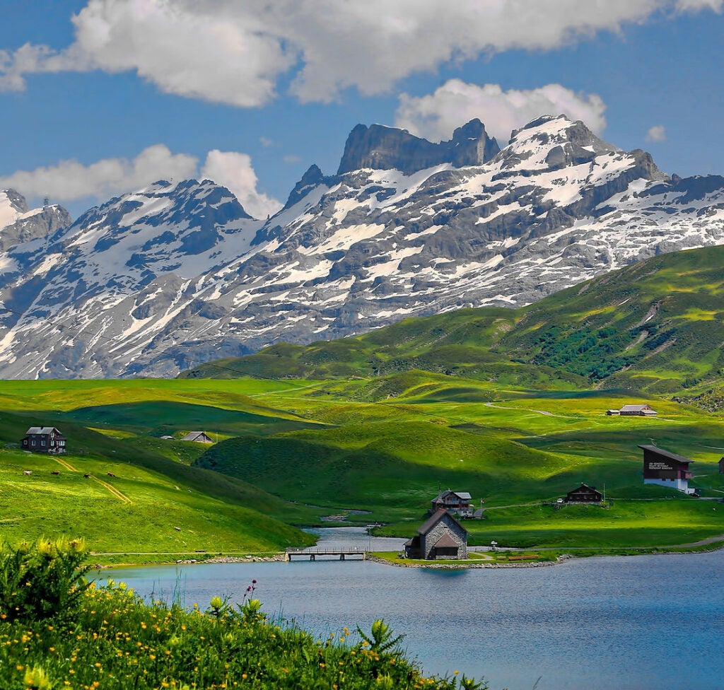 landscape of a hillside and mountain in France with a small village at the bootom of the hillside near a lake