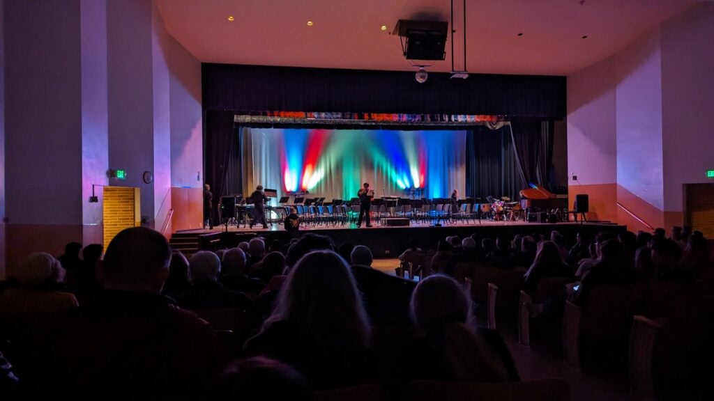 Shadows of people in seats looking at stage.