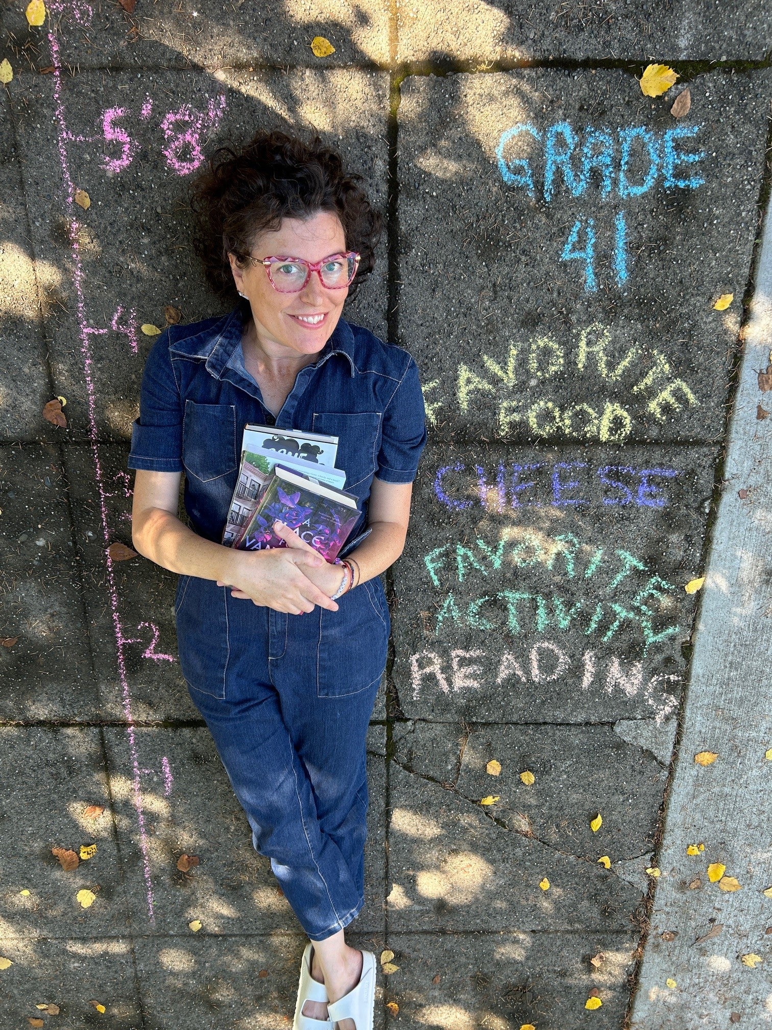 Ms Johnson lying on the sidewalk with a "back to school" chalk information board beside her