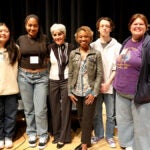 Students, school staff, and White House staff stand on a stage during career day