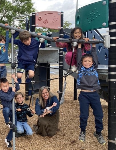 6 students and a teacher on the Adams playground having fun