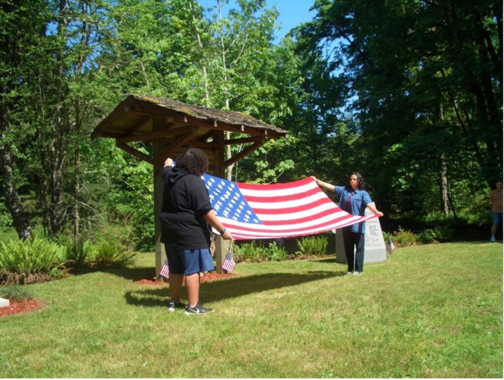 2 adults outdoors holding a flag