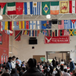 Auditorium with people in audience and flags in ceiling.