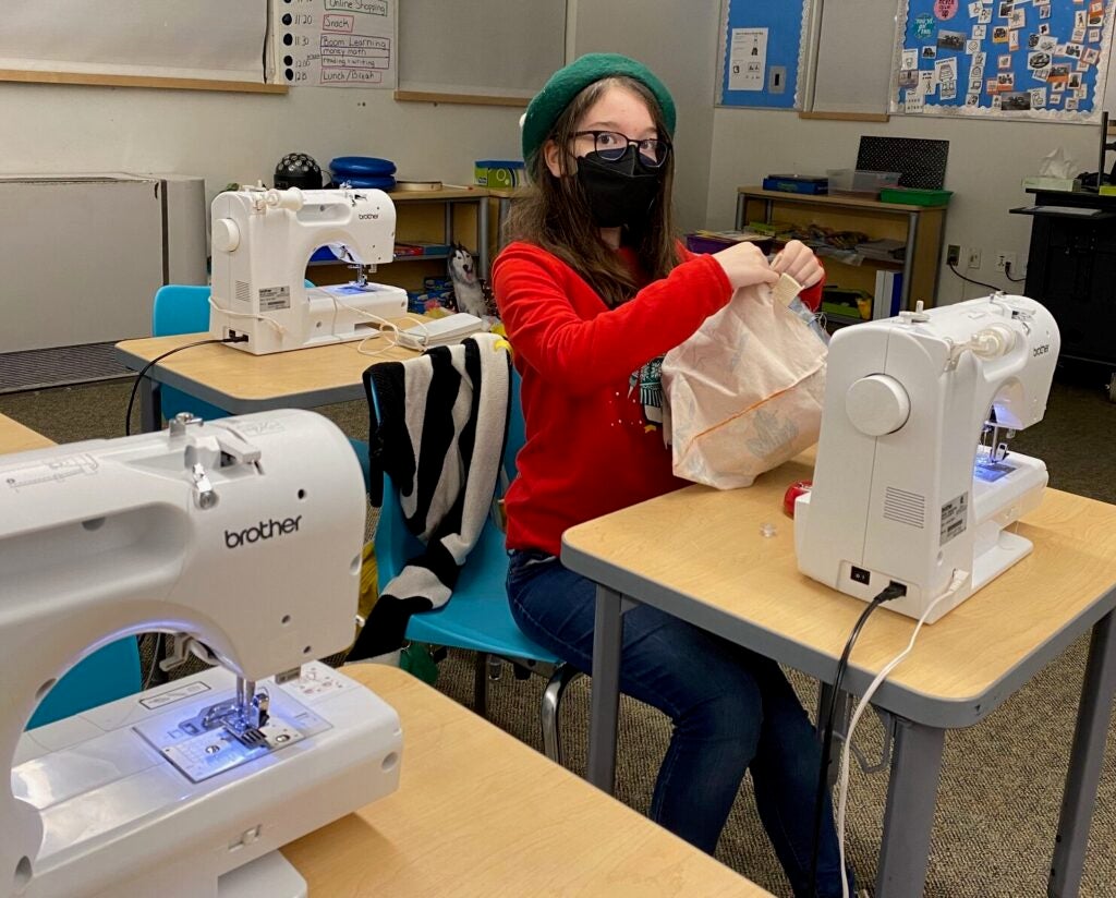 picture of a student in read at a sewing machine